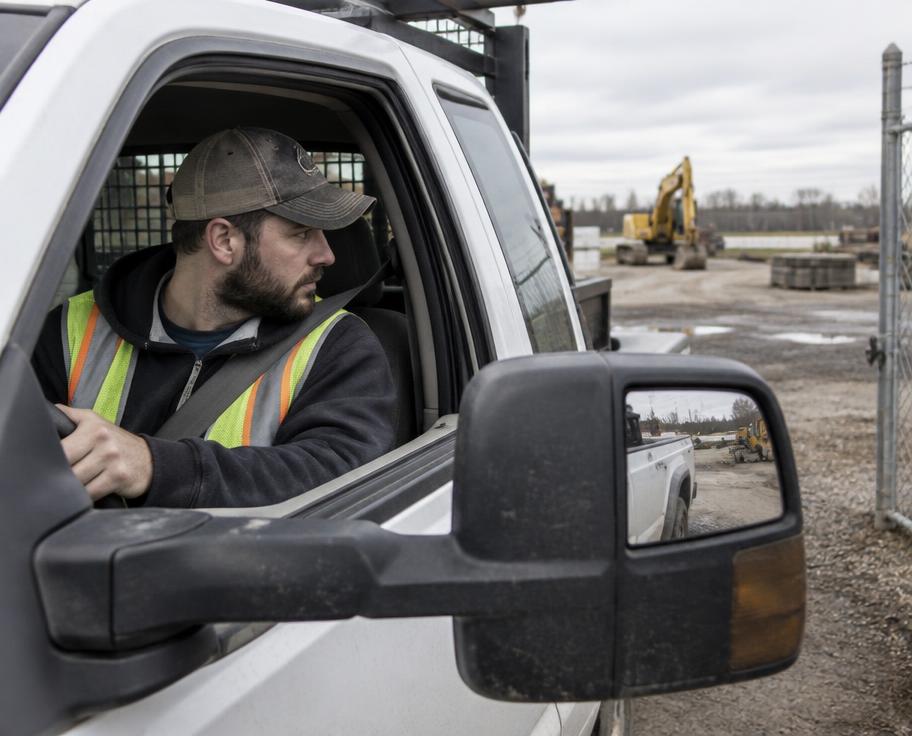 Work truck driver checking mirrors before leaving a jobsite yard